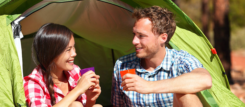 Una coppia sorridente davanti alla loro tenda in un campeggio dell'Alto Adige