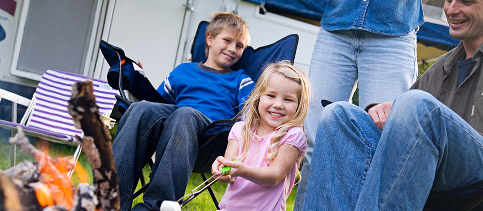 Famiglia felice in un campeggio in Alto Adige griglia marshmallows sul falò