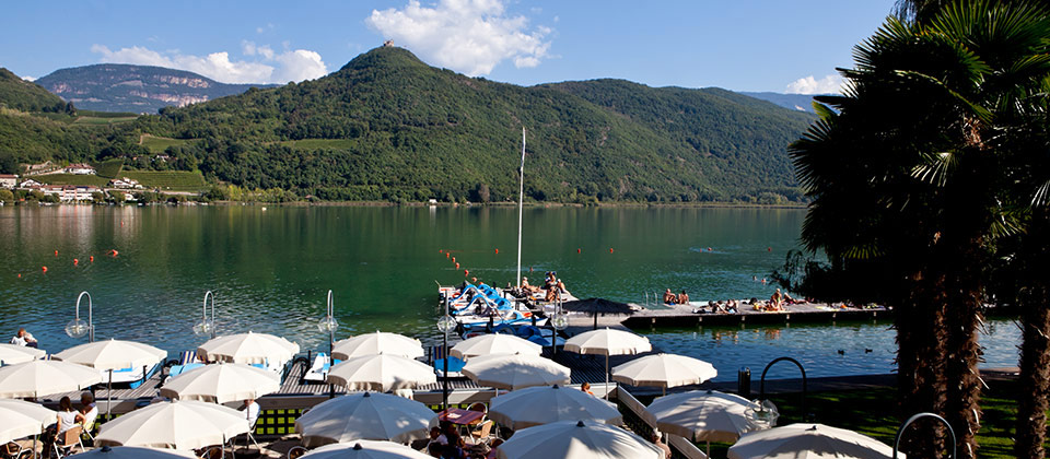 Eine Reihe von Sonnenschirmen am Ufer des Kalterer Sees