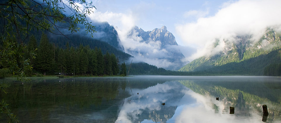 The lake of Dobbiaco in Pusteria with the surrounding peaks covered by clouds