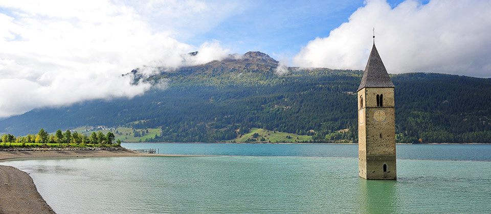 Der zum Teil versunkene Glockenturm am Reschen-See, mitten im glasklarem Wasser 