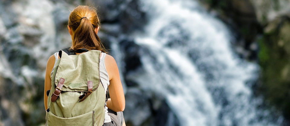 Eine Frau die sich vor einem Wasserfall im Eisacktal ausruht